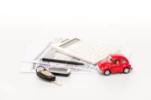keys, calculator, insurance certificates and red toy car on white surface