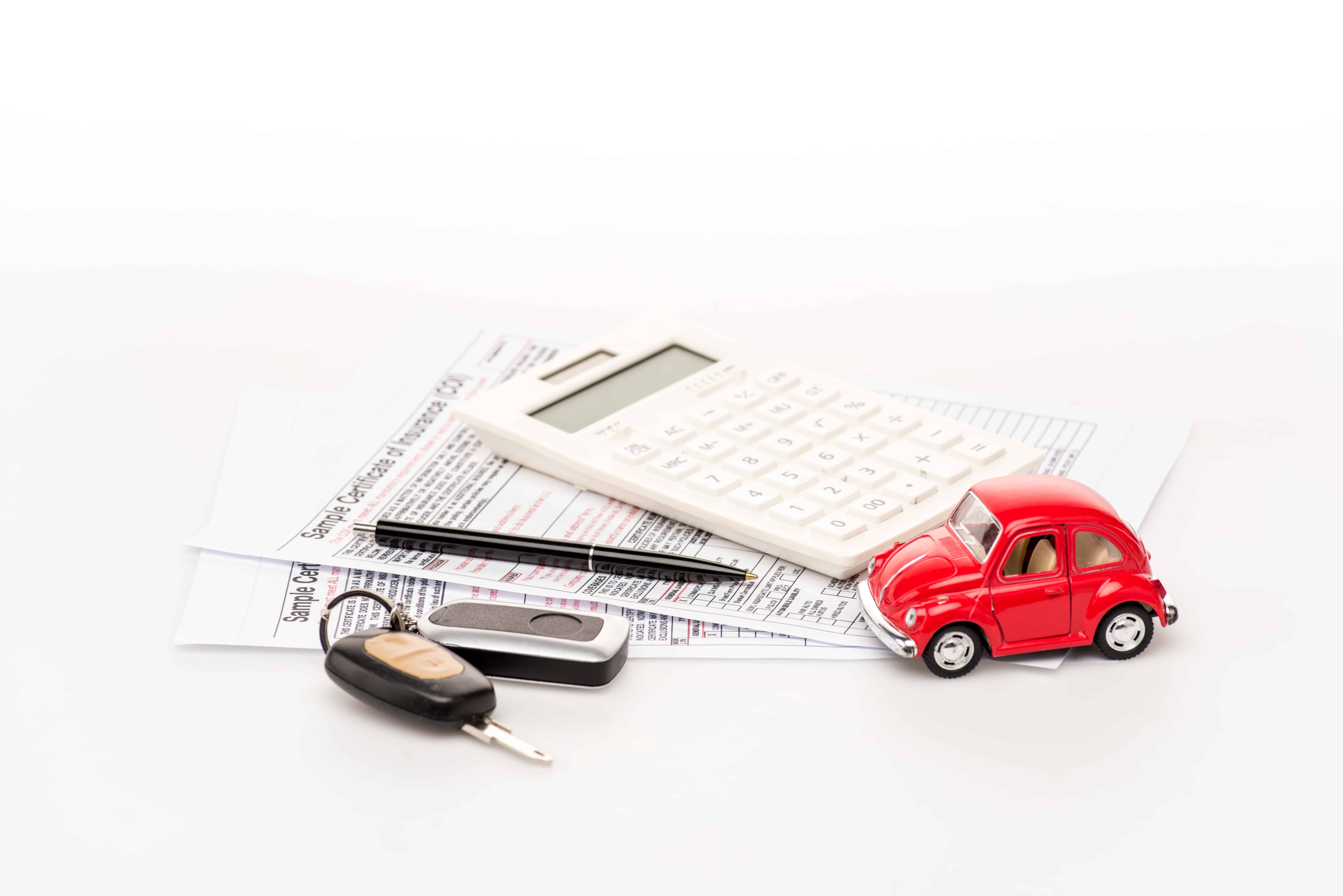 keys, calculator, insurance certificates and red toy car on white surface